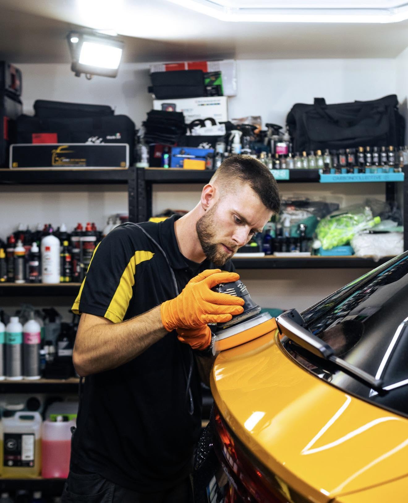 Josh carefully polishing a vehicle in the JMM Detailing studio